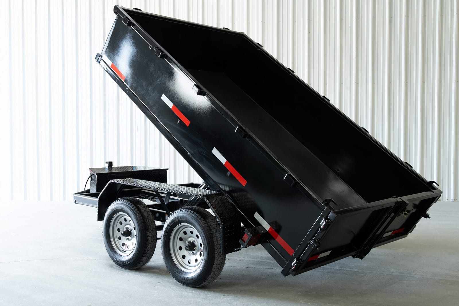 Hydraulic dump trailer raised and dumping a load of gravel